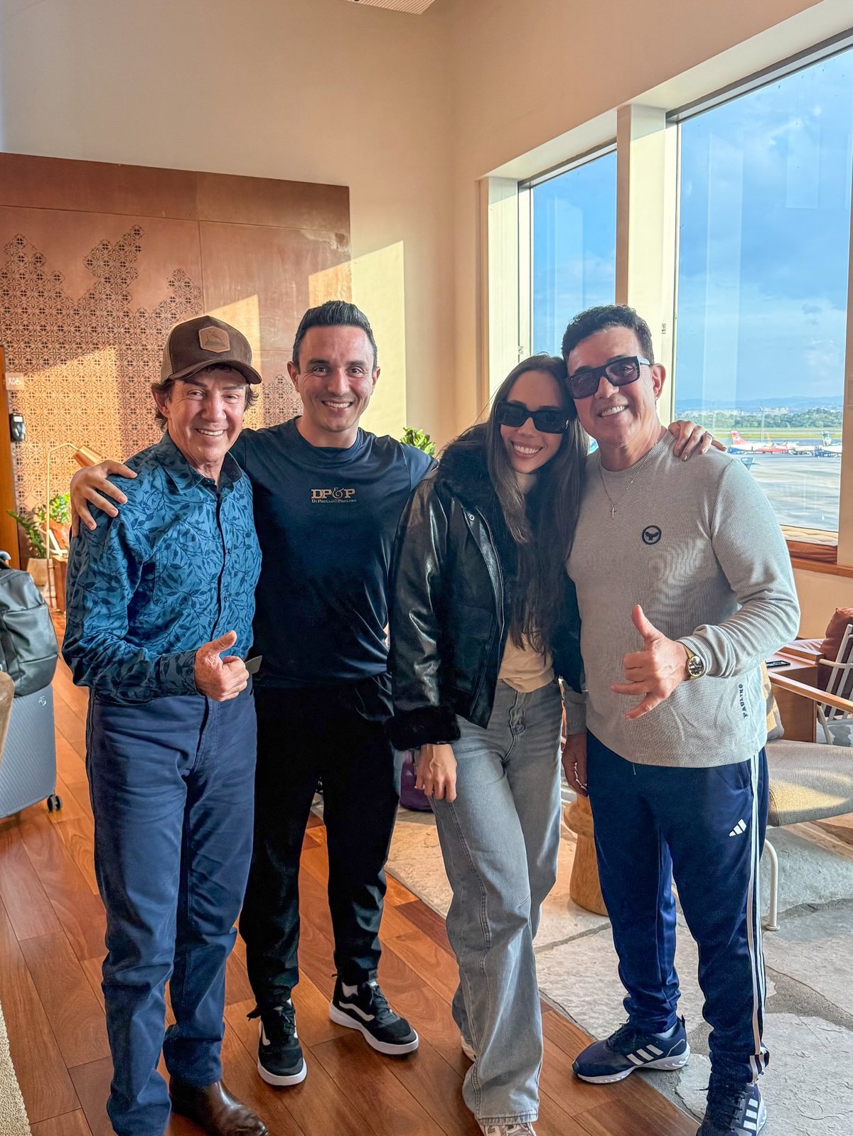 No lounge do aeroporto, em reunião com a equipe, com a pista ao fundo